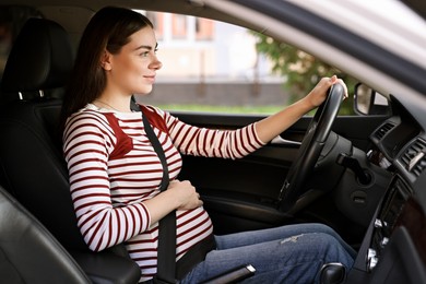 Pregnant woman with safety belt driving car