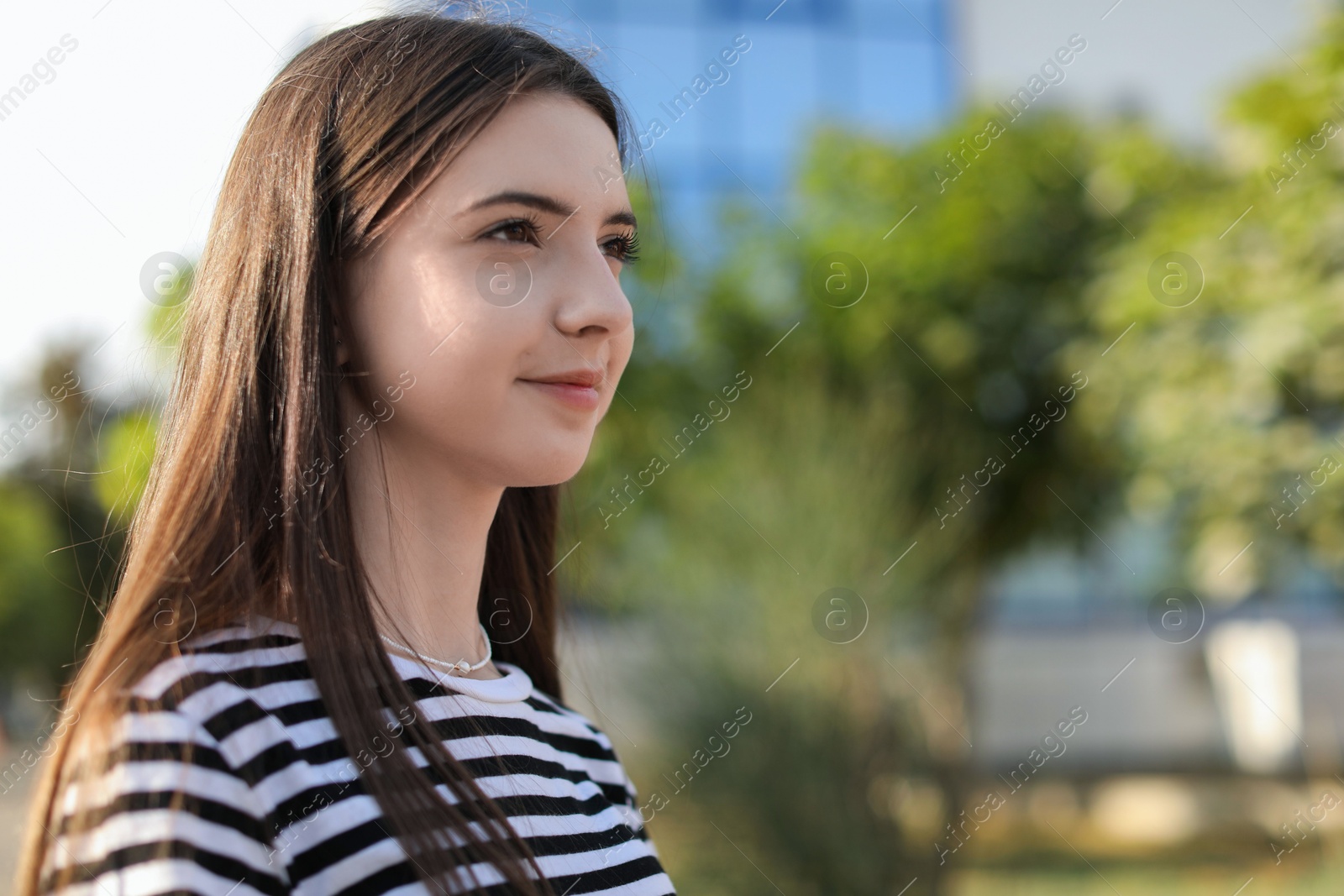 Photo of Portrait of beautiful teenage girl on city street. Space for text