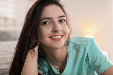 Portrait of smiling teenage girl on bed at home