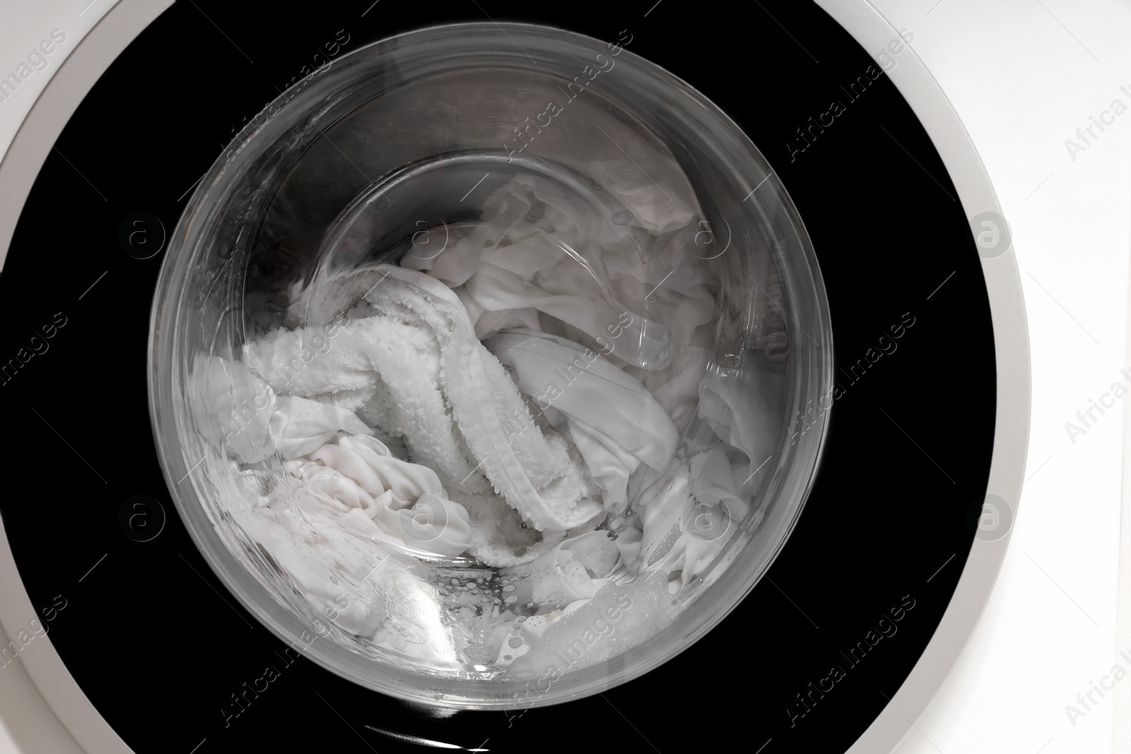 Photo of Washing machine with clothes as background, closeup