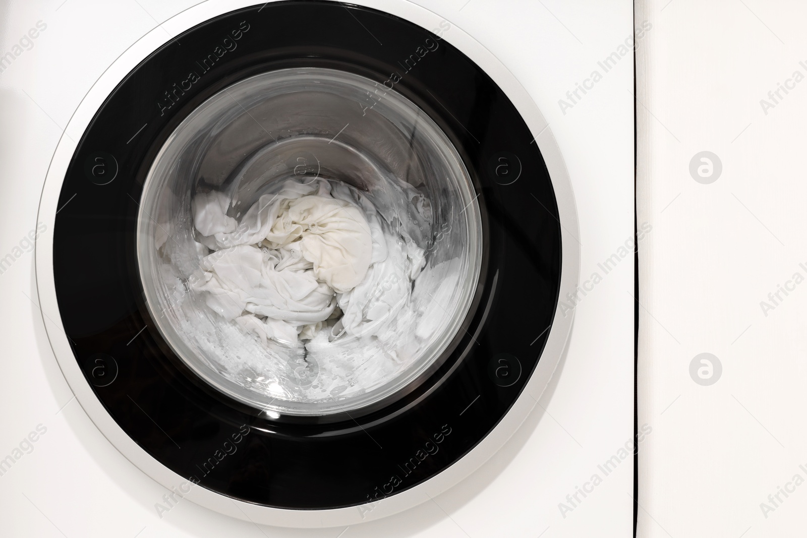 Photo of Washing machine with clothes as background, closeup