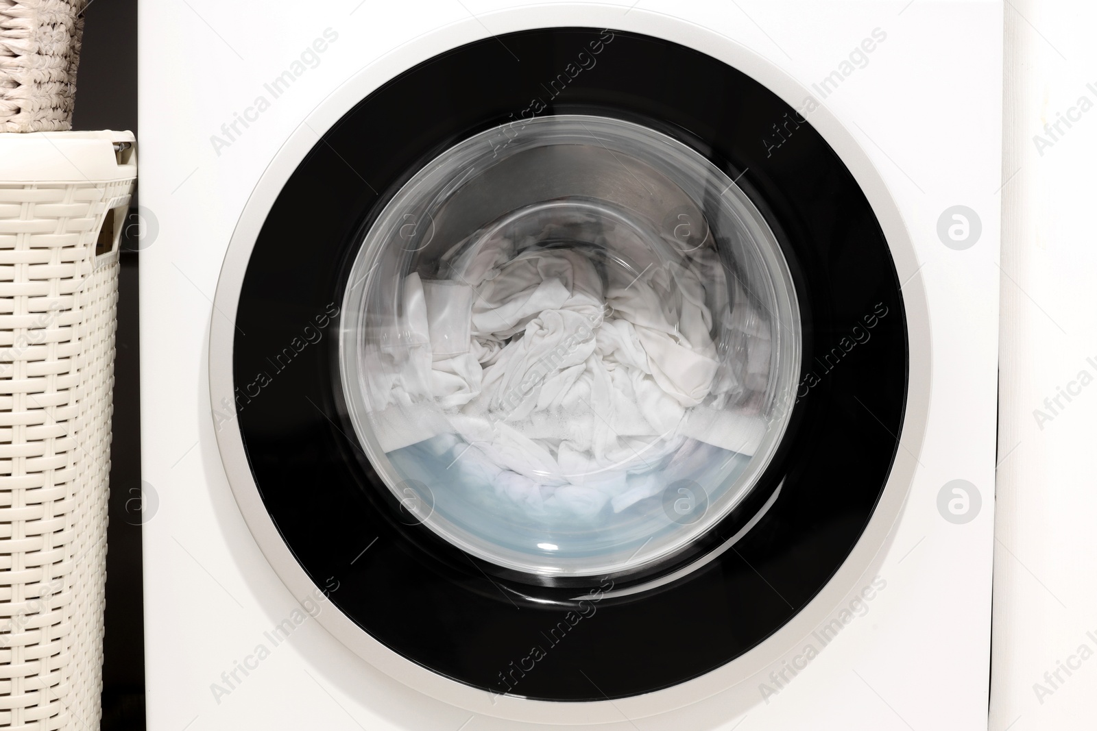 Photo of Washing machine with clothes as background, closeup