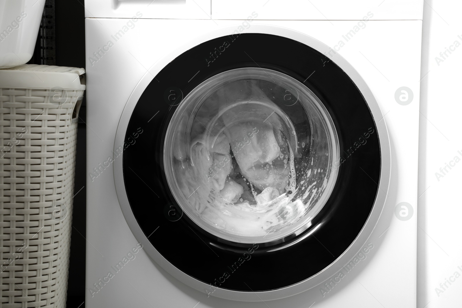 Photo of Washing machine with clothes and suds as background, closeup