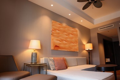 Photo of Comfortable furniture and beautiful abstract painting on wall in room