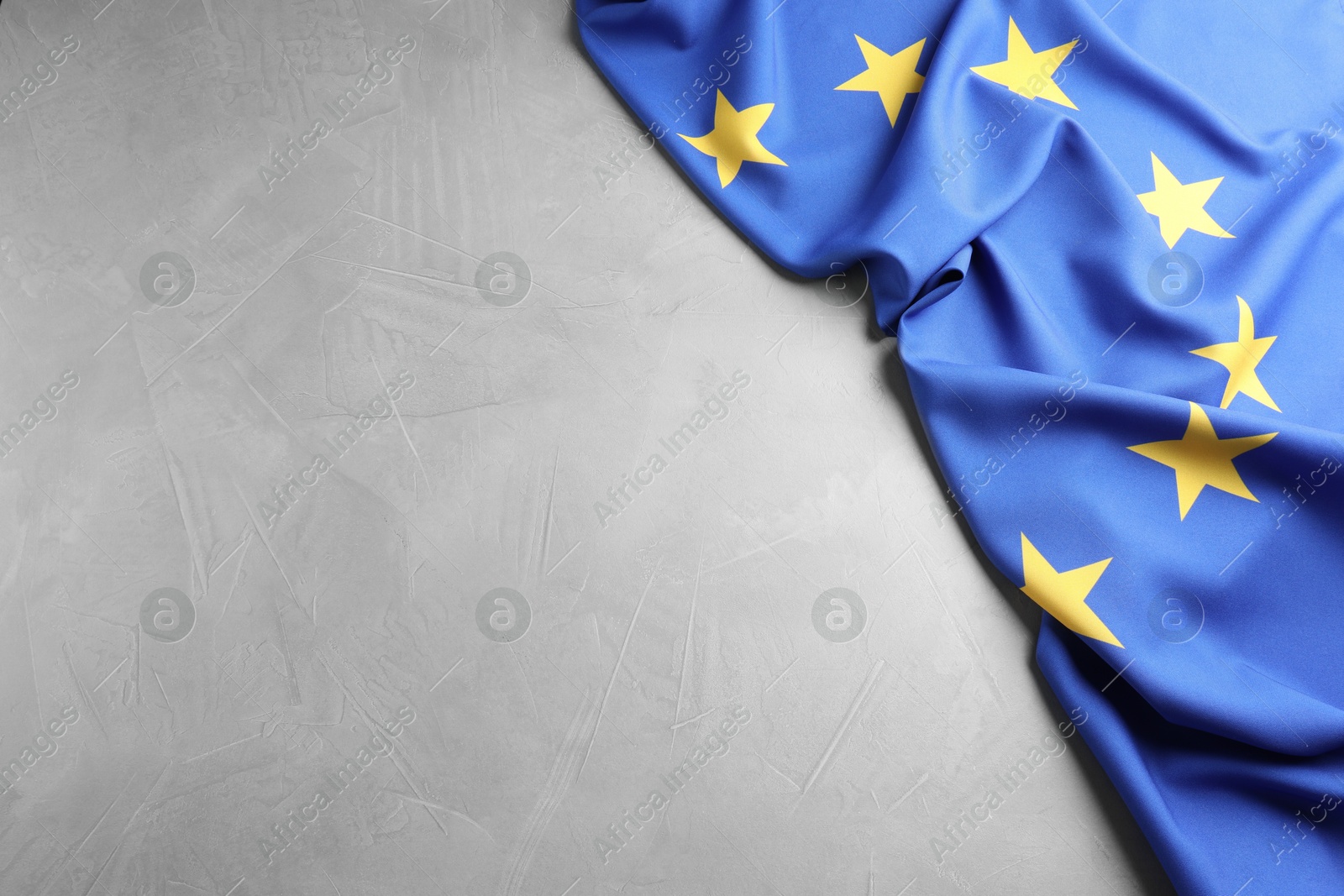 Photo of Flag of European Union on grey table, above view. Space for text