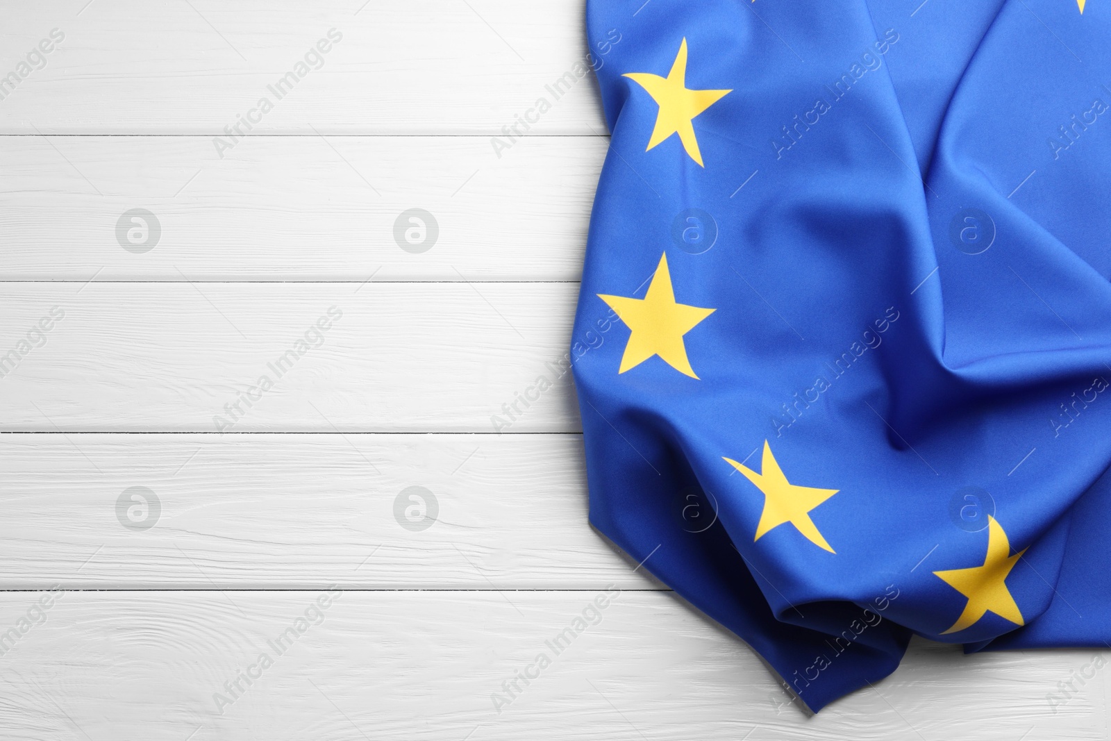 Photo of Flag of European Union on white wooden table, top view. Space for text