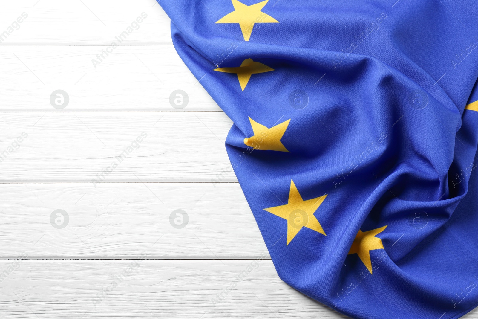 Photo of Flag of European Union on white wooden table, top view. Space for text