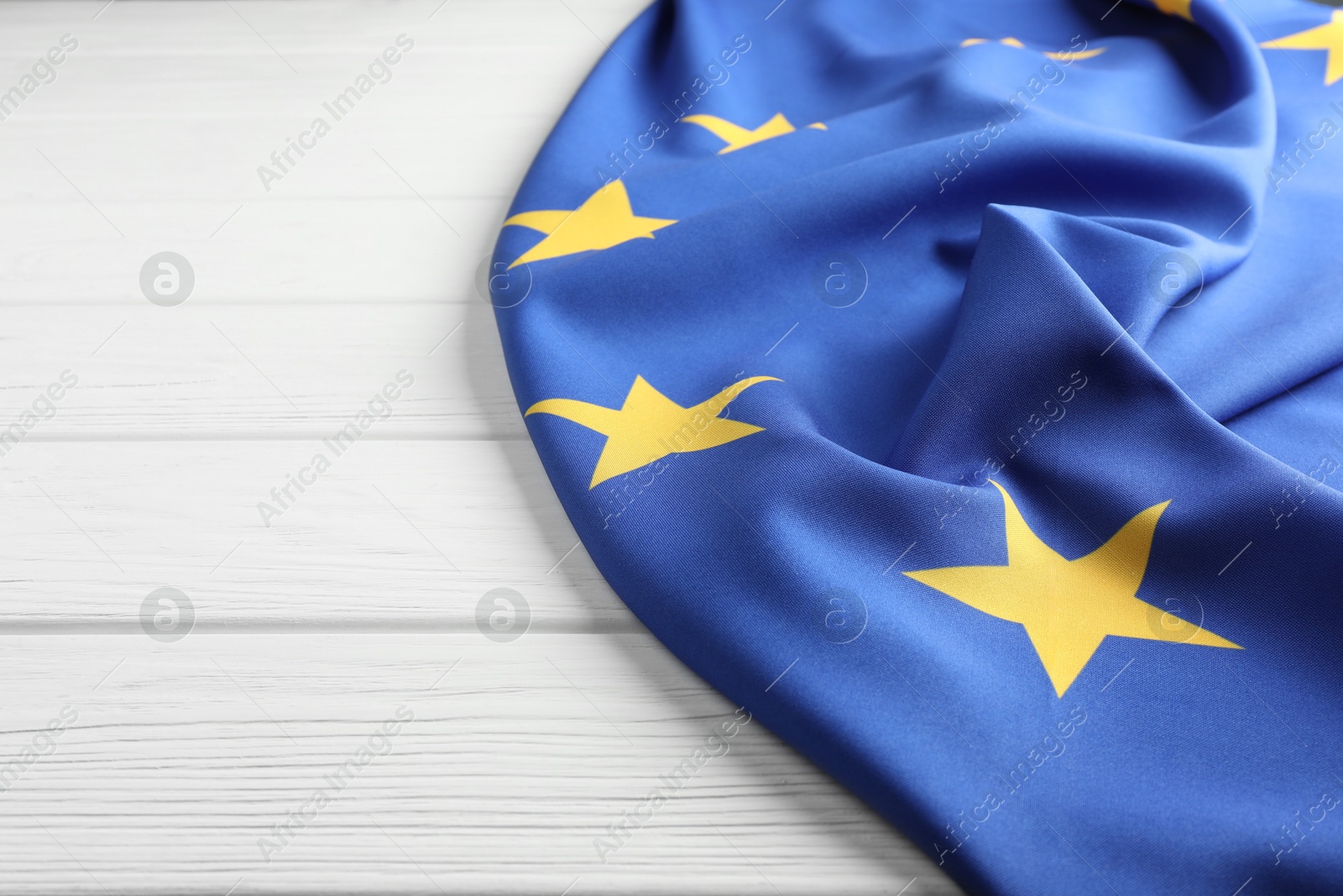 Photo of Flag of European Union on white wooden table, closeup. Space for text