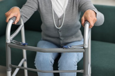 Photo of Senior woman with walking frame on sofa at home, closeup