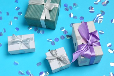 Photo of Many different gift boxes and shiny confetti on light blue background