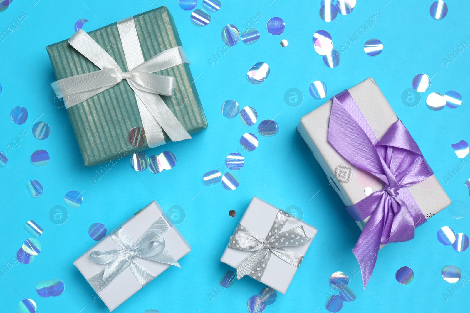 Photo of Many different gift boxes and shiny confetti on light blue background, flat lay