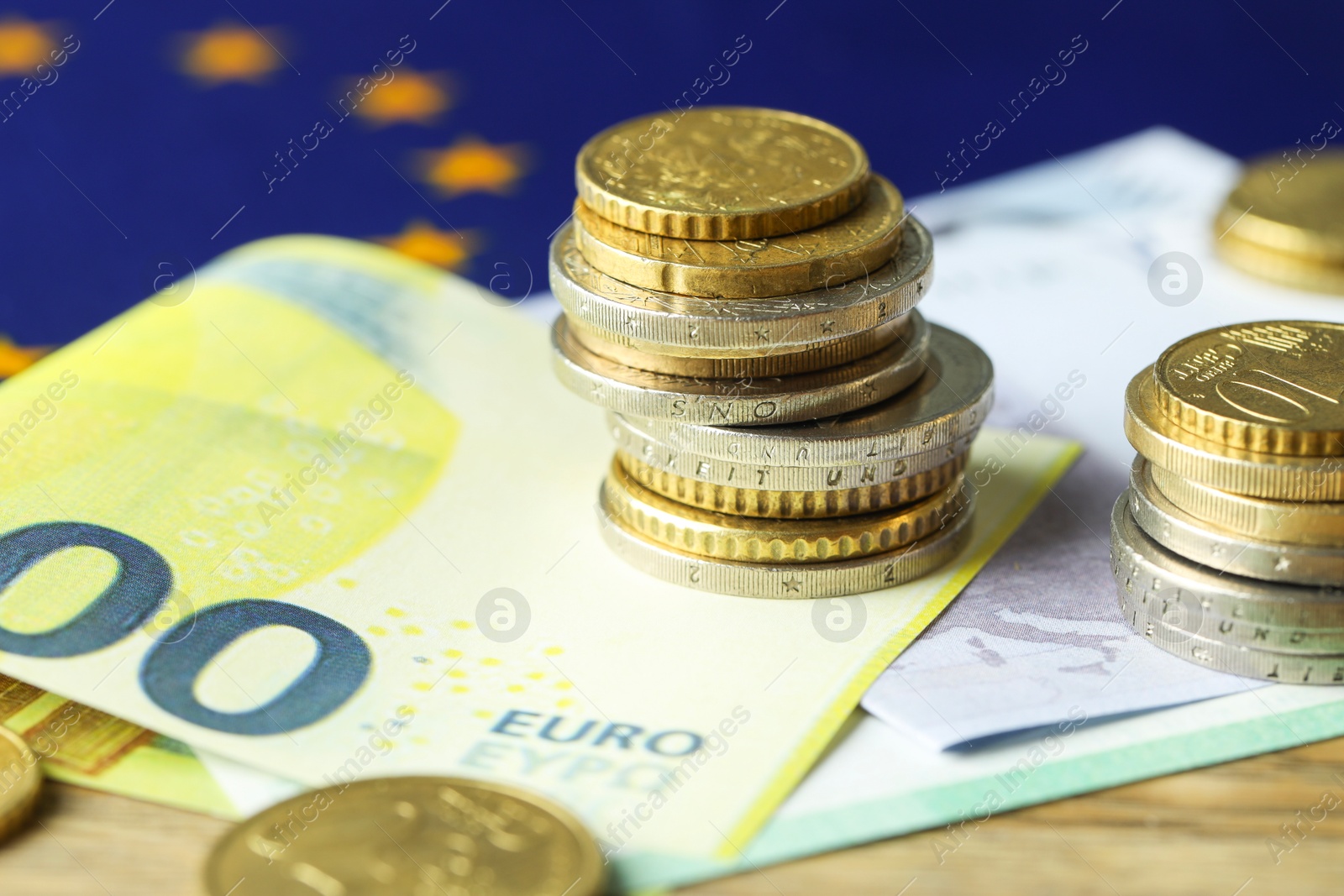 Photo of Euro banknotes, coins and European Union flag on table, closeup