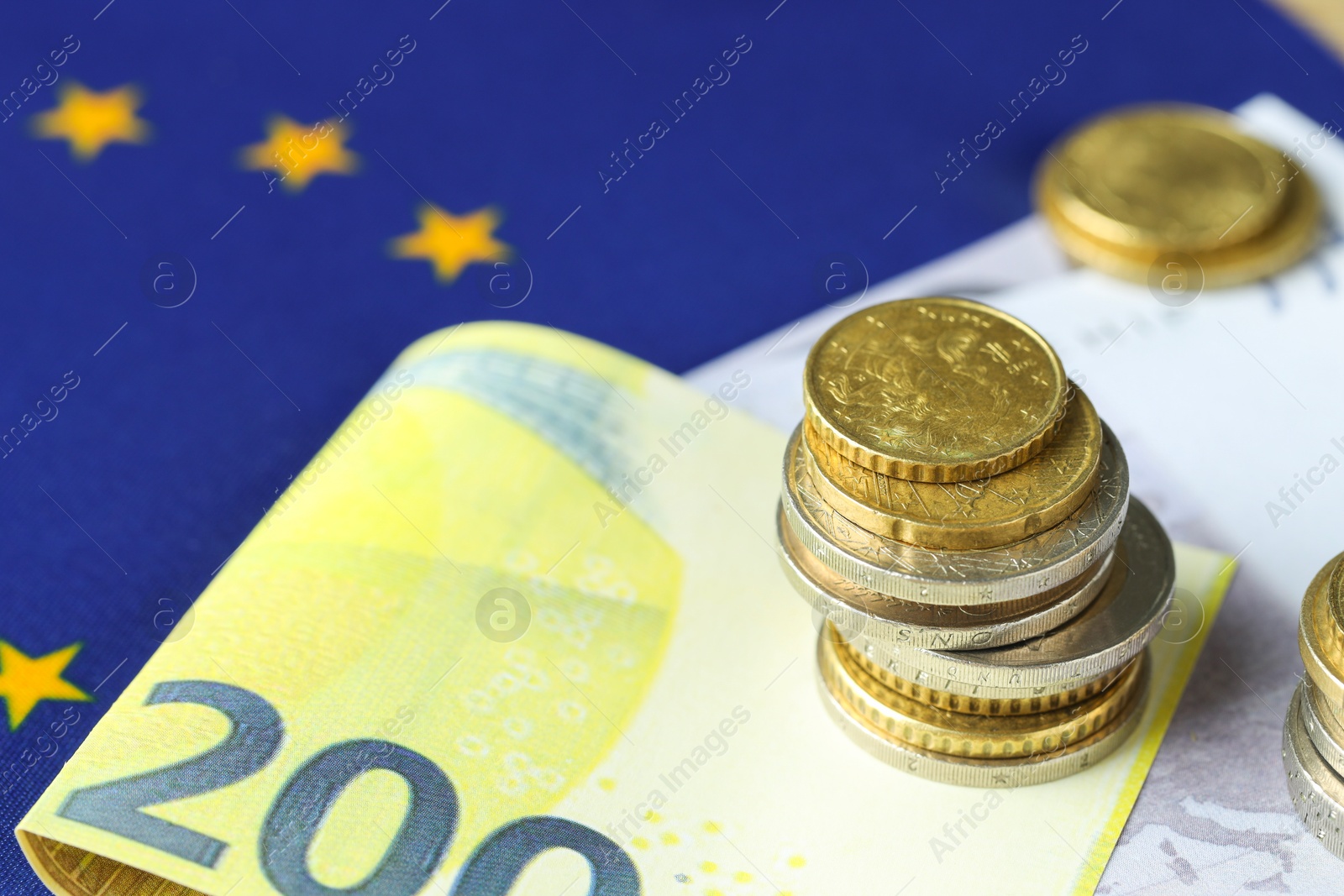 Photo of Euro banknotes and coins on European Union flag, closeup