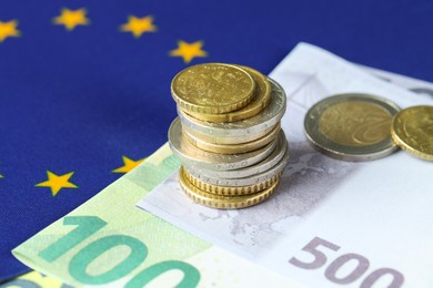 Photo of Euro banknotes and coins on European Union flag, closeup