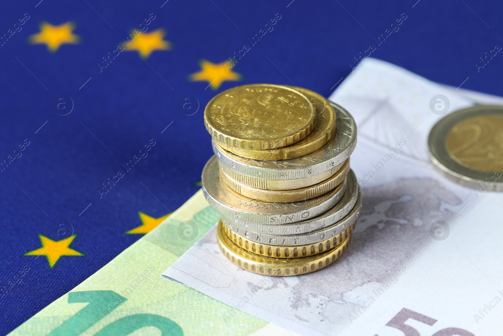 Photo of Euro banknotes and coins on European Union flag, closeup