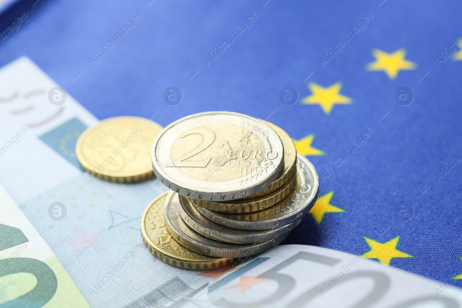 Photo of Euro banknotes and coins on European Union flag, closeup