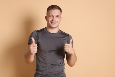 Photo of Happy winner showing thumbs up on beige background