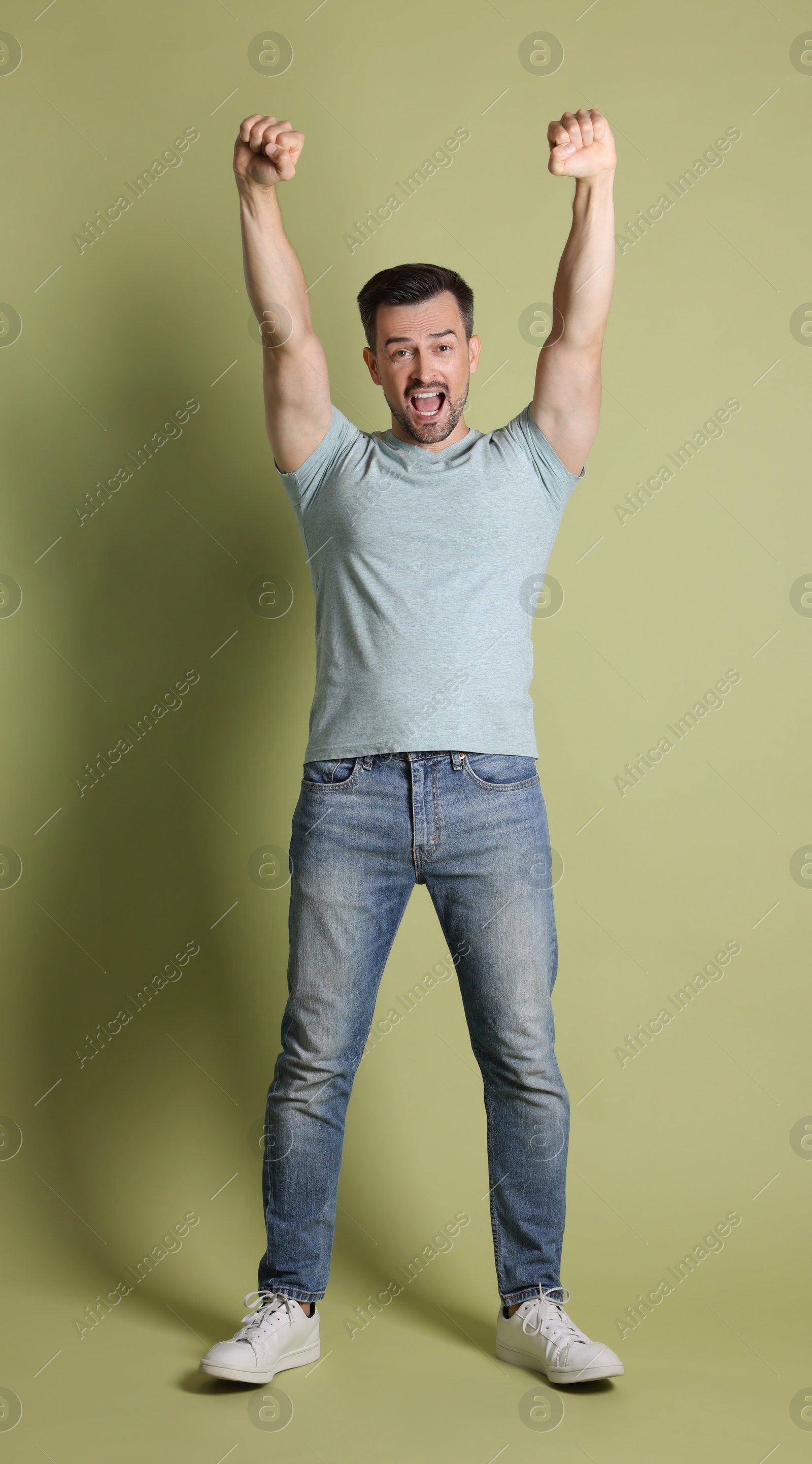 Photo of Portrait of happy winner on pale olive background