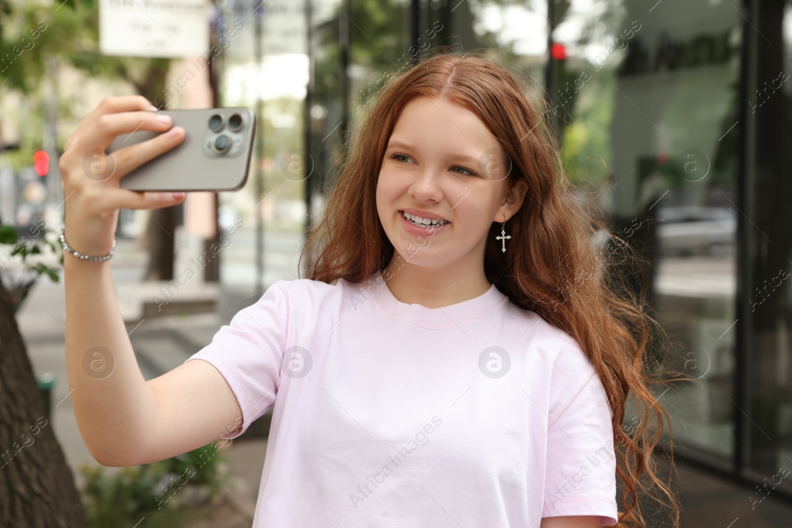 Photo of Beautiful teenage girl taking selfie with smartphone outdoors