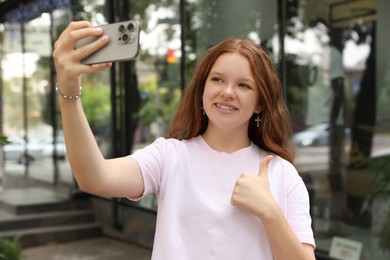 Photo of Beautiful teenage girl taking selfie with smartphone outdoors