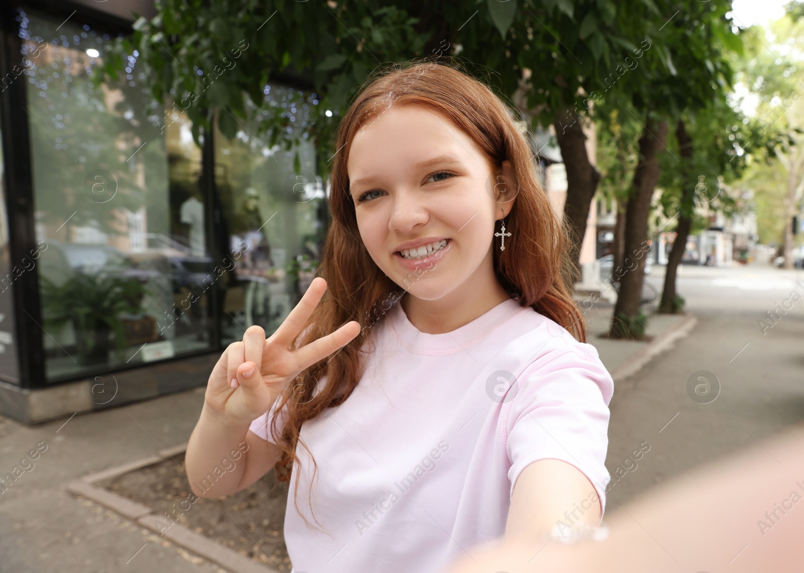 Photo of Beautiful teenage girl taking selfie on city street