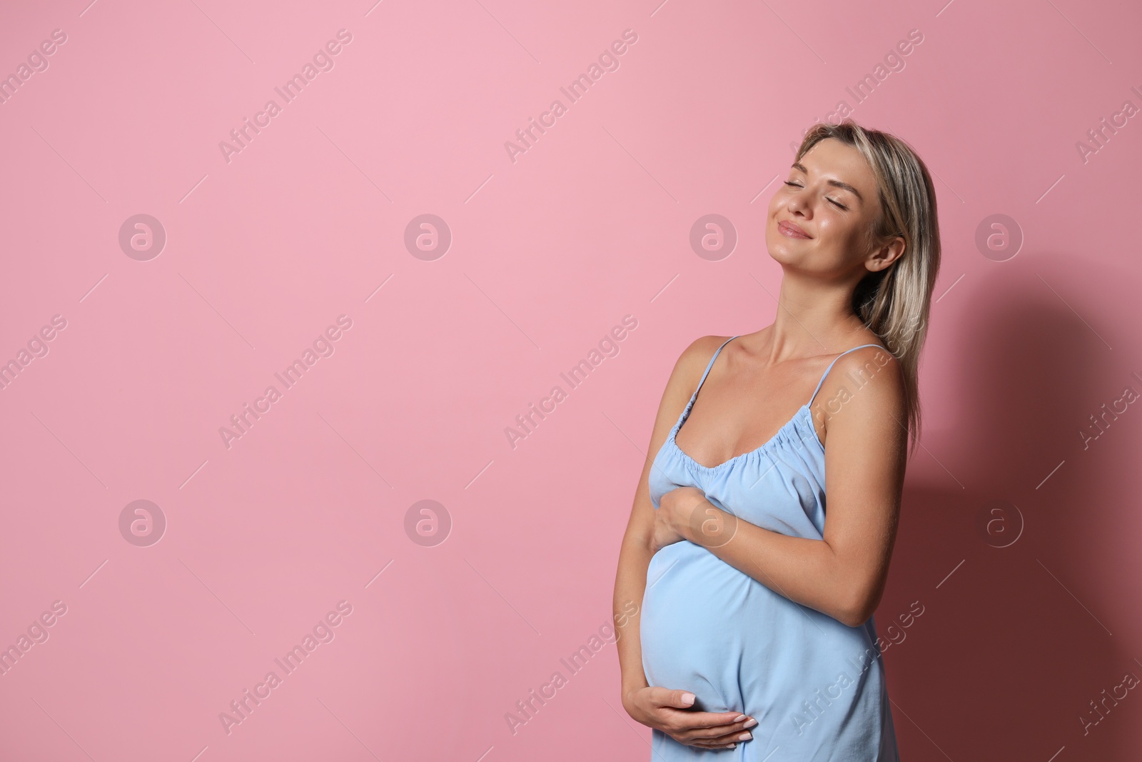 Photo of Portrait of beautiful pregnant woman on pink background, space for text