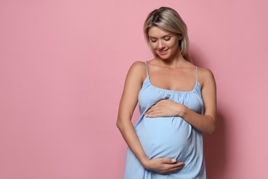 Portrait of beautiful pregnant woman on pink background, space for text