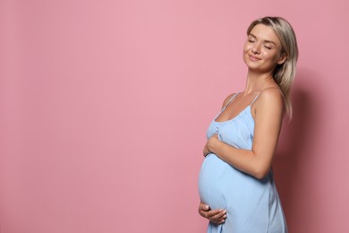 Photo of Portrait of beautiful pregnant woman on pink background, space for text