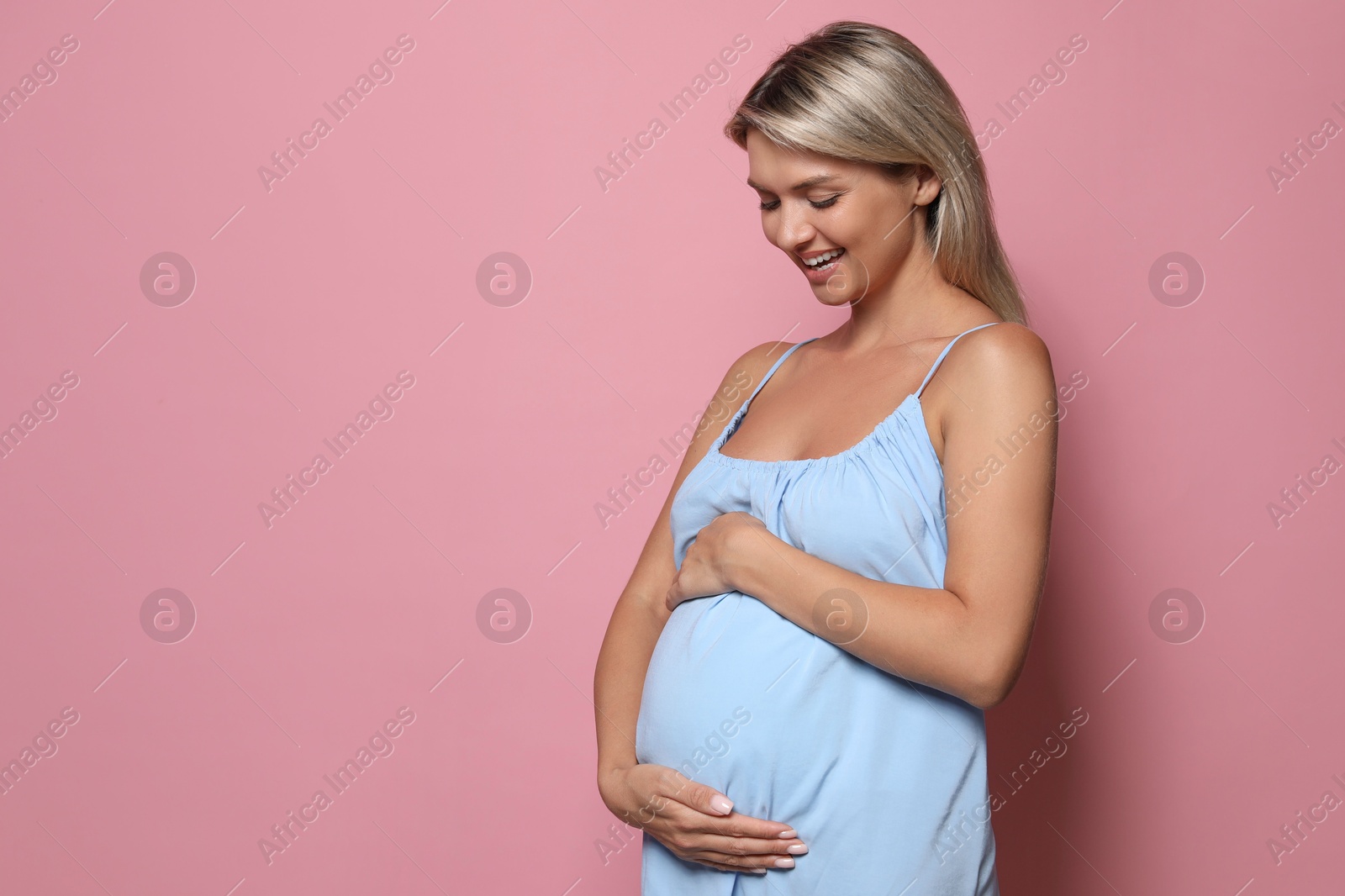 Photo of Portrait of beautiful pregnant woman on pink background, space for text