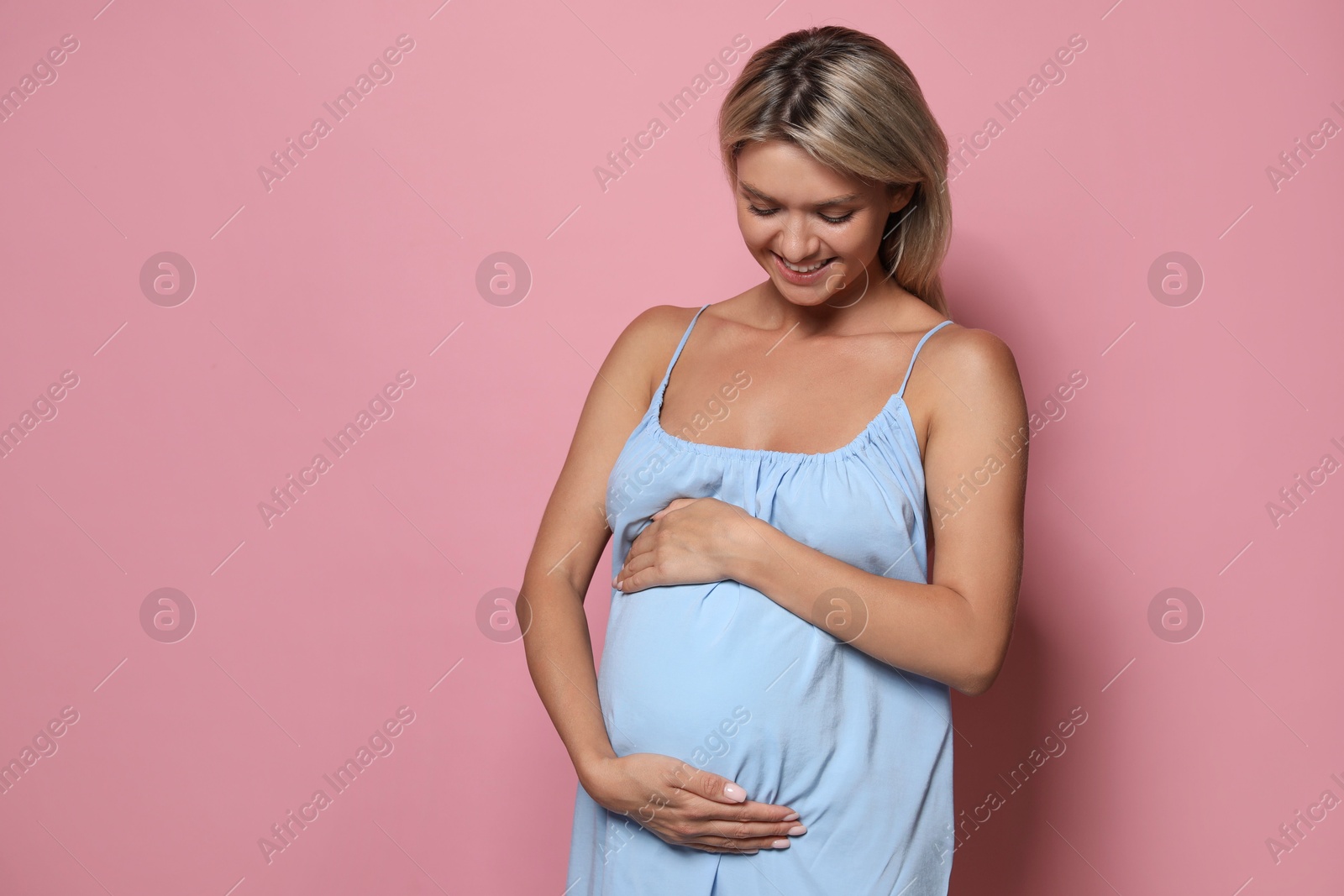 Photo of Portrait of beautiful pregnant woman on pink background, space for text