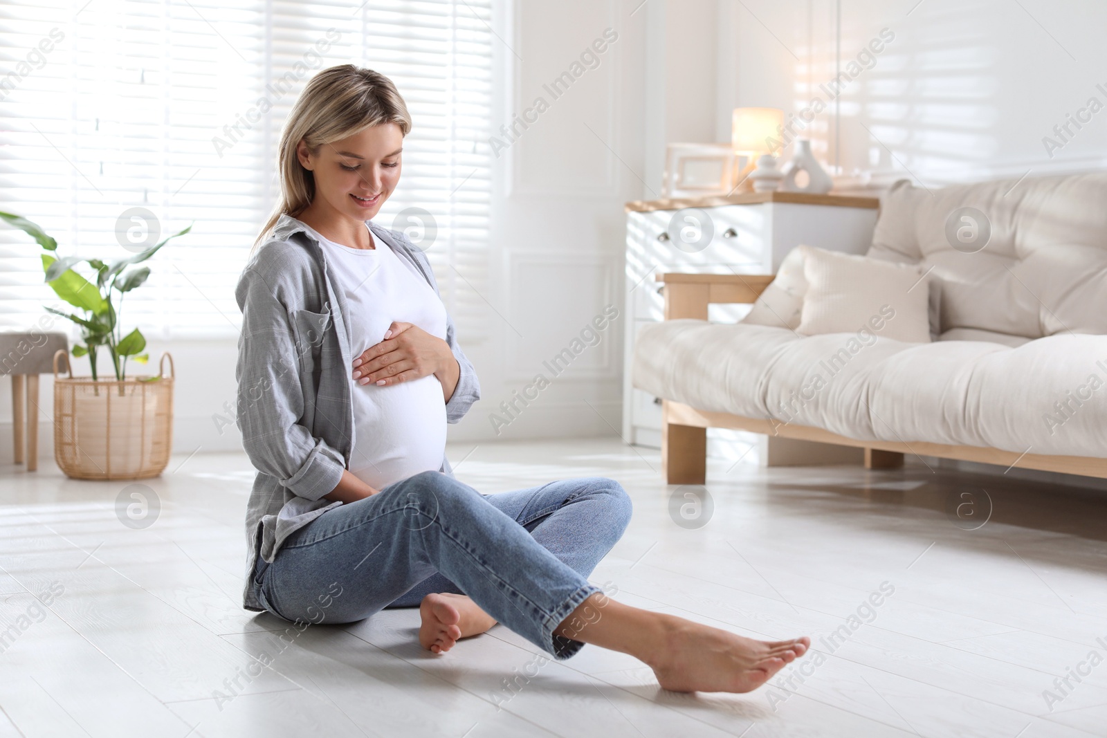 Photo of Portrait of beautiful pregnant woman on floor at home