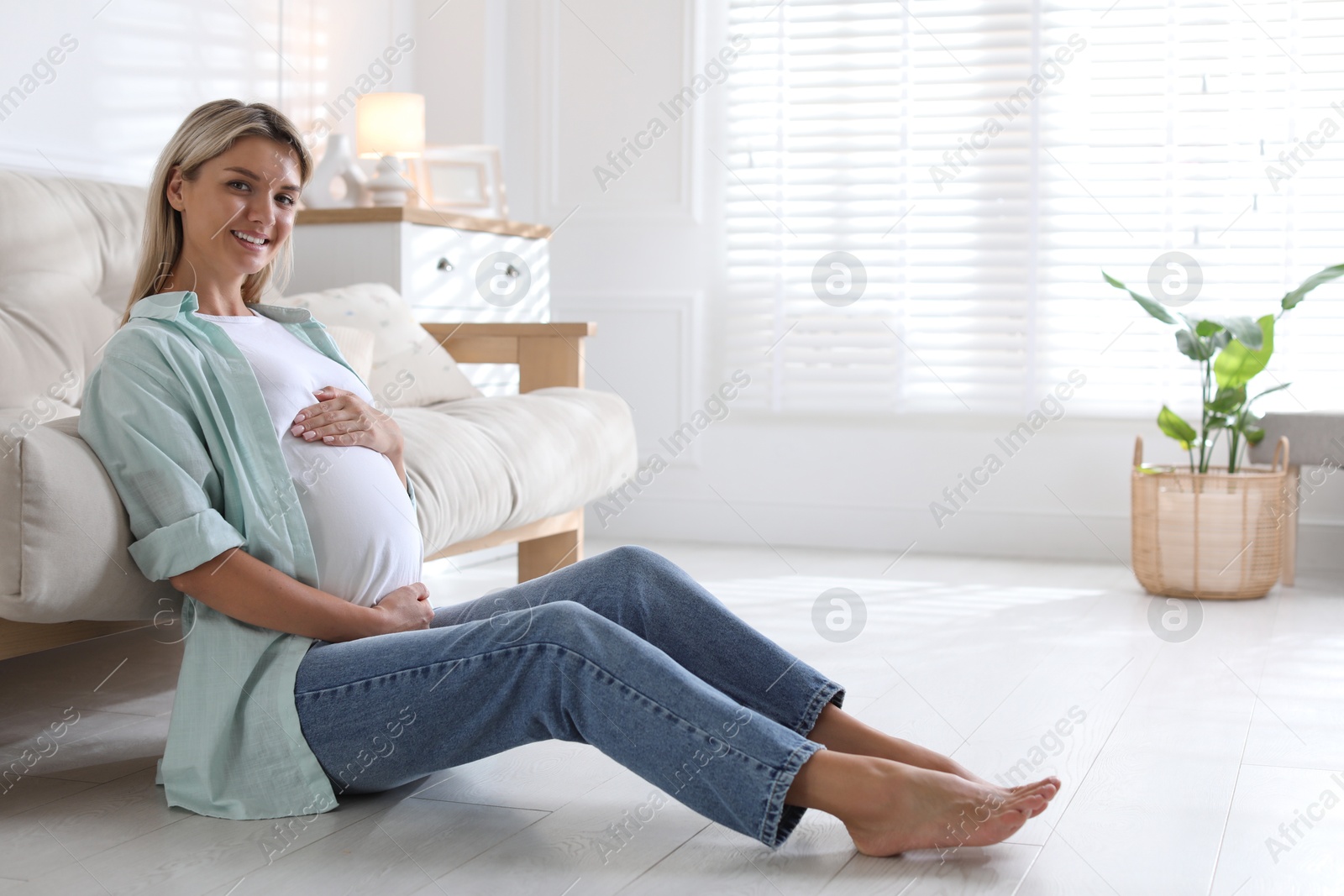 Photo of Portrait of beautiful pregnant woman on floor at home