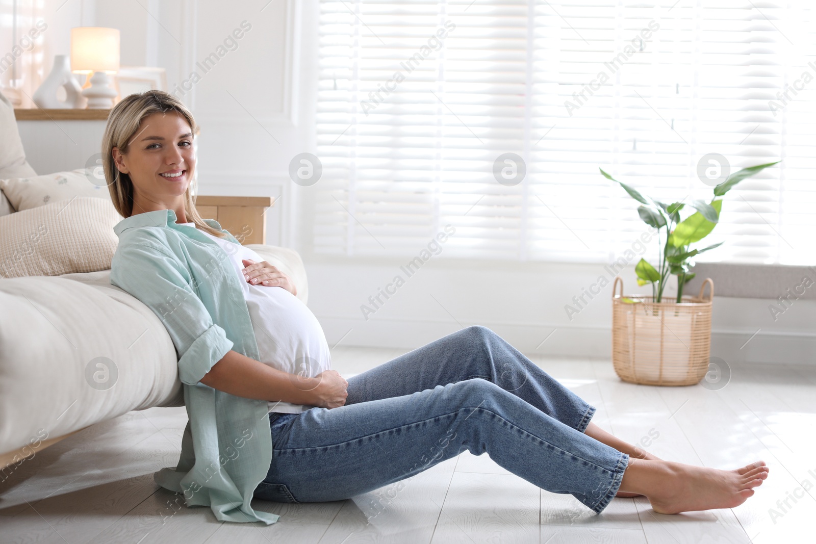 Photo of Portrait of beautiful pregnant woman on floor at home