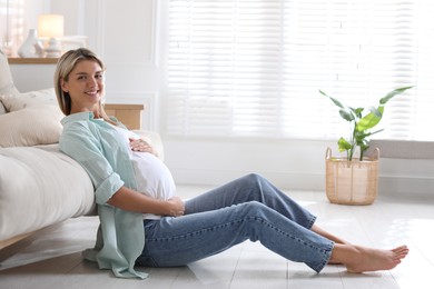 Photo of Portrait of beautiful pregnant woman on floor at home