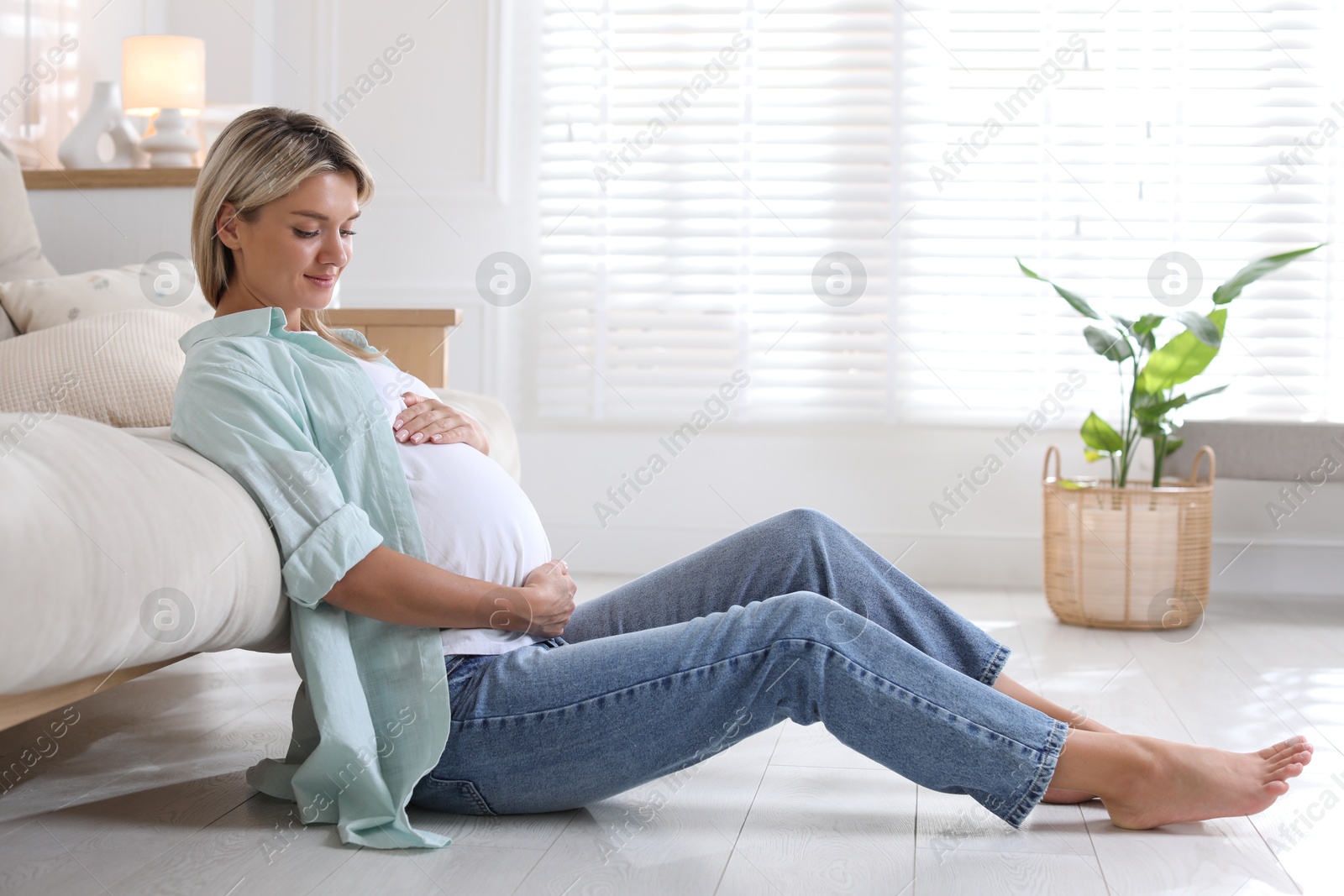 Photo of Portrait of beautiful pregnant woman on floor at home