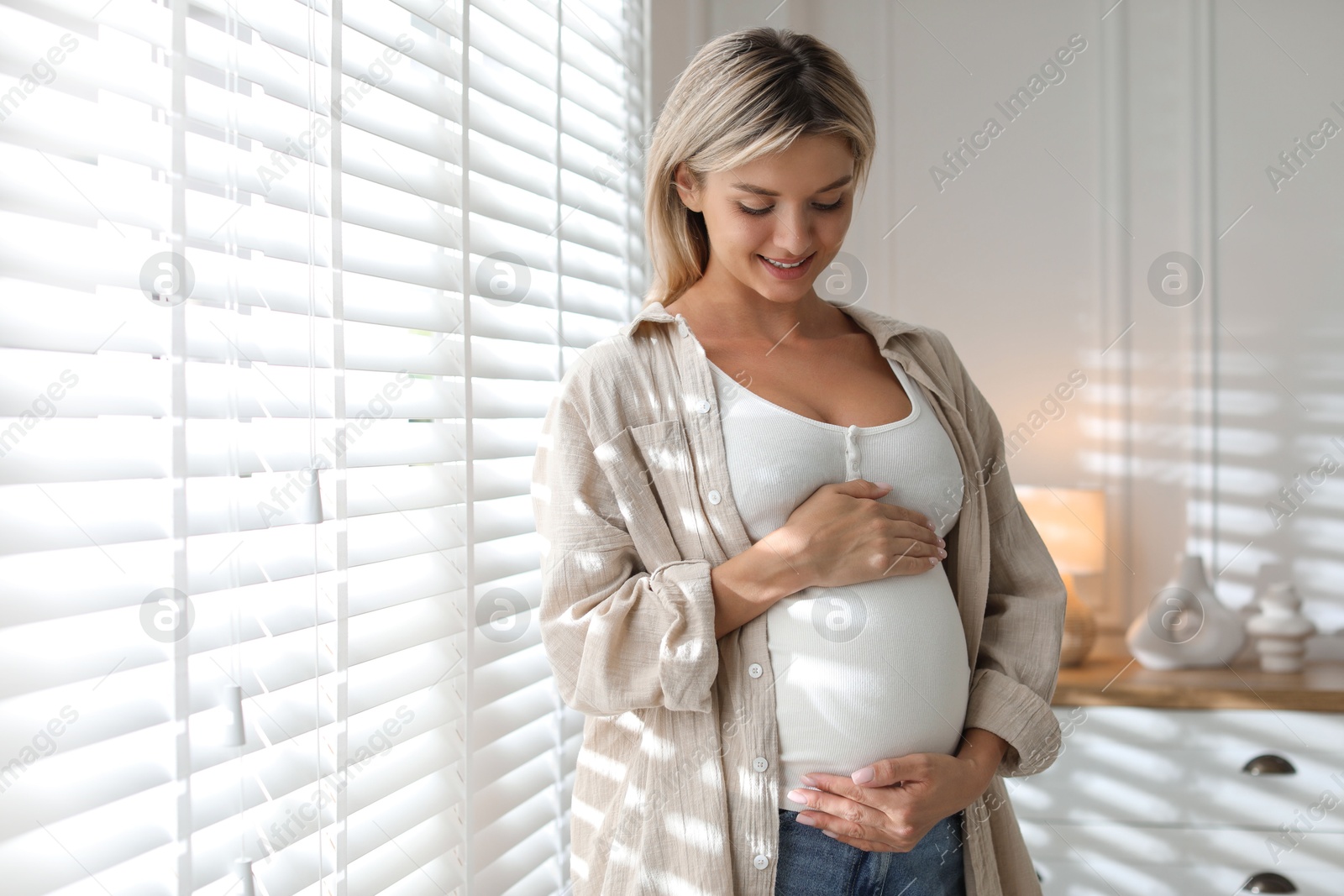 Photo of Portrait of beautiful pregnant woman near window at home