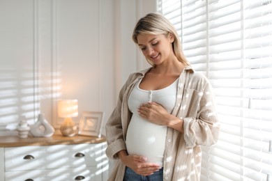 Photo of Portrait of beautiful pregnant woman near window at home