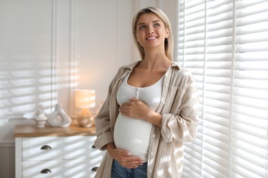 Photo of Portrait of beautiful pregnant woman near window at home