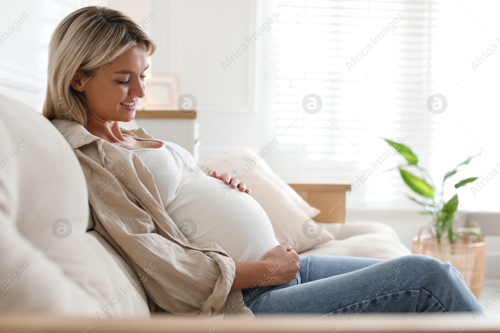 Photo of Portrait of beautiful pregnant woman on sofa at home