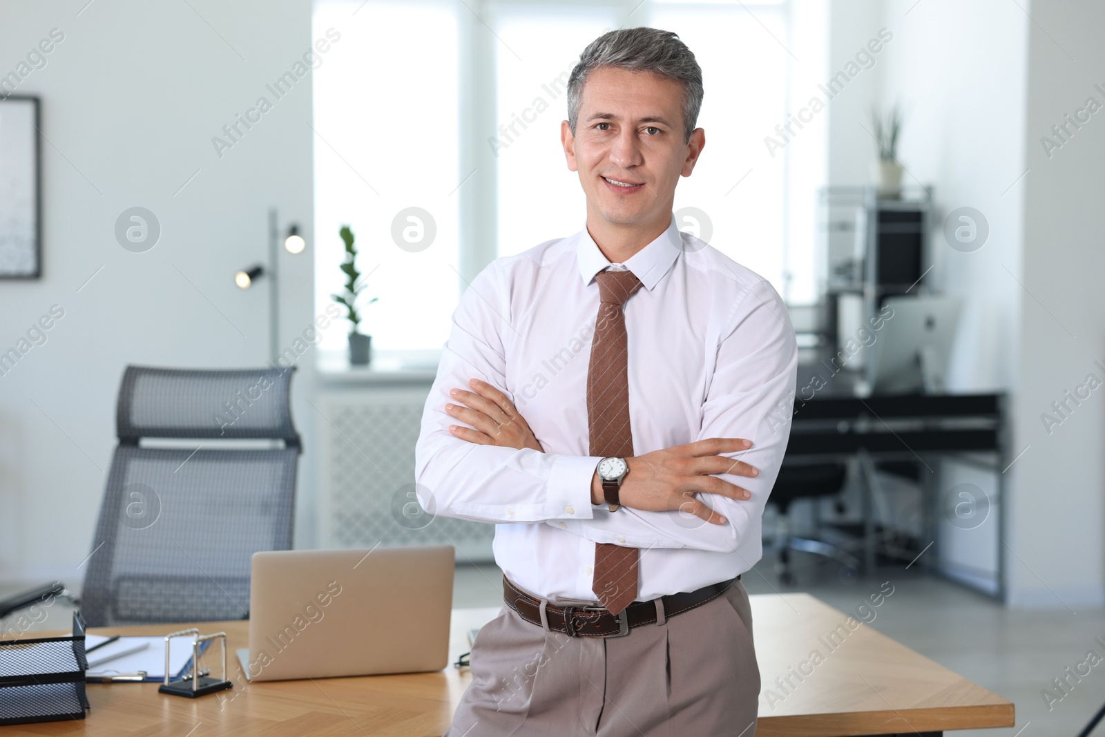 Photo of Portrait of smiling middle aged man with crossed arms in office