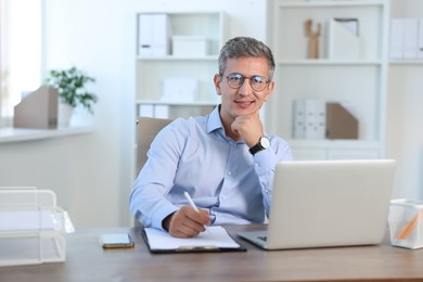 Photo of Portrait of smiling middle aged man at table in office