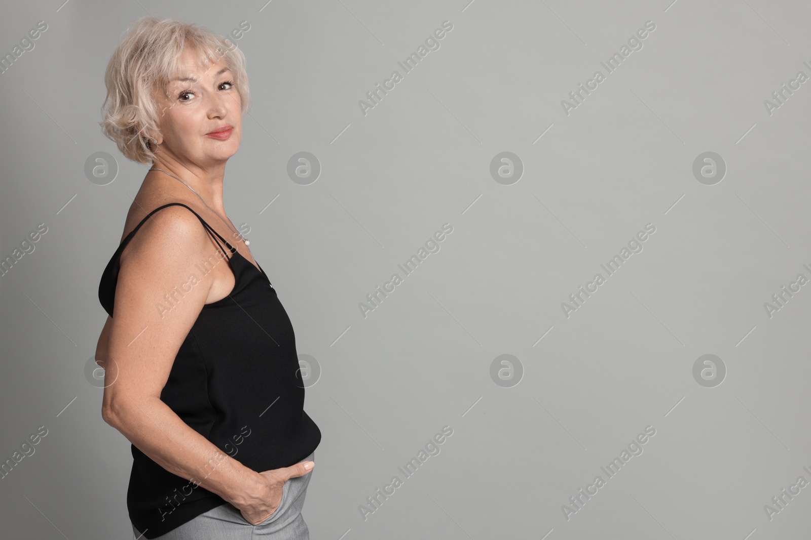 Photo of Portrait of beautiful senior woman on light grey background, space for text