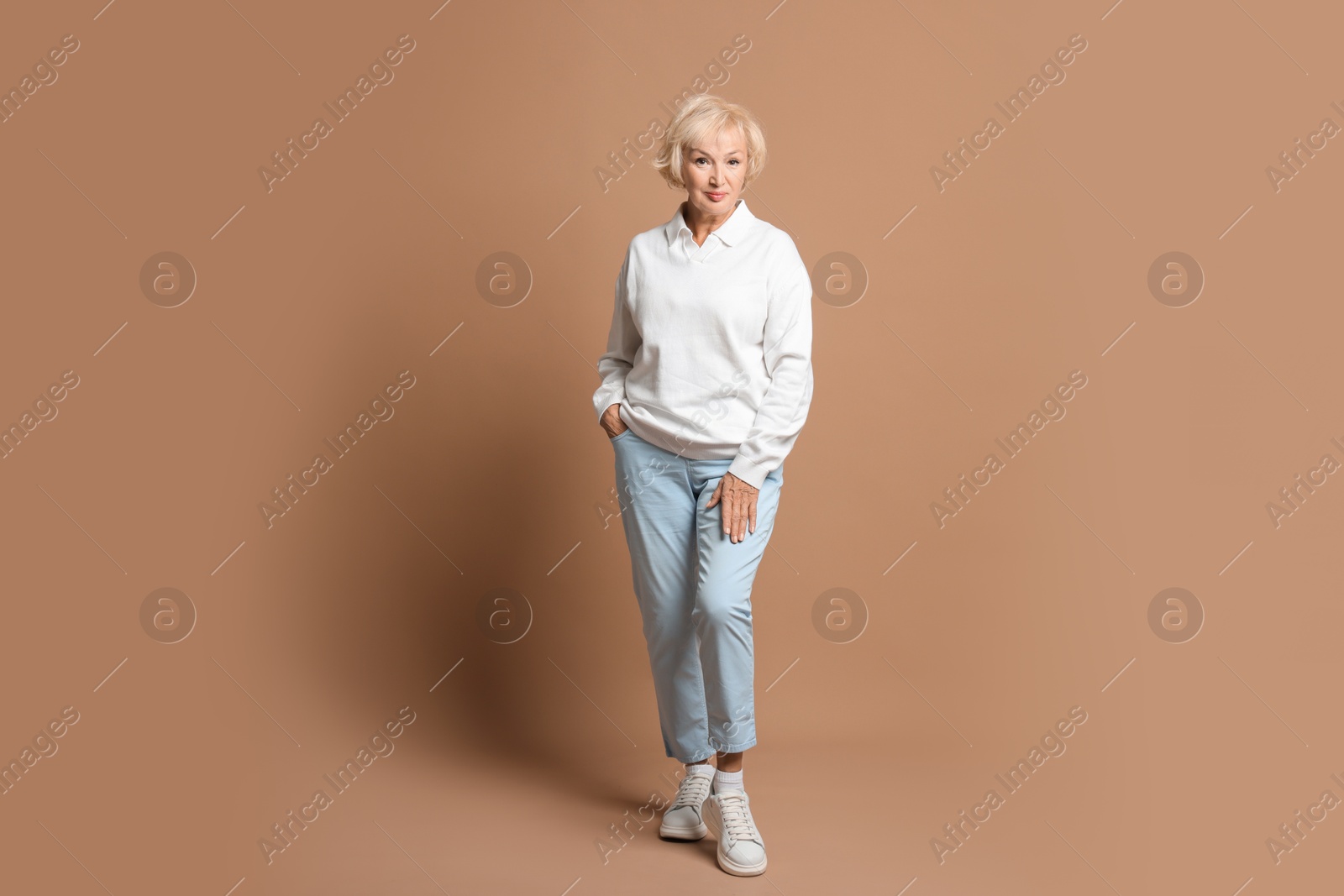 Photo of Full length portrait of beautiful senior woman on light brown background