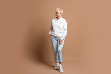 Photo of Full length portrait of beautiful senior woman on light brown background