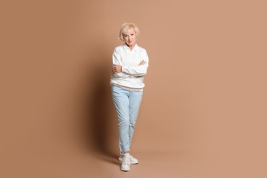 Full length portrait of beautiful senior woman on light brown background