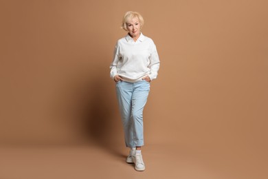 Photo of Full length portrait of beautiful senior woman on light brown background