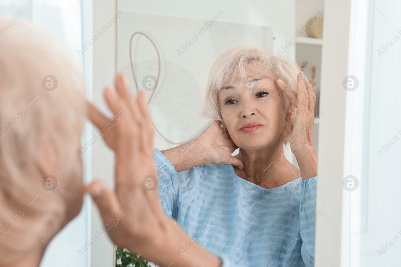 Photo of Beautiful senior woman near mirror at home