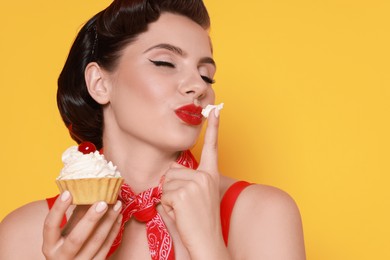 Photo of Pin-up woman eating cupcake on orange background