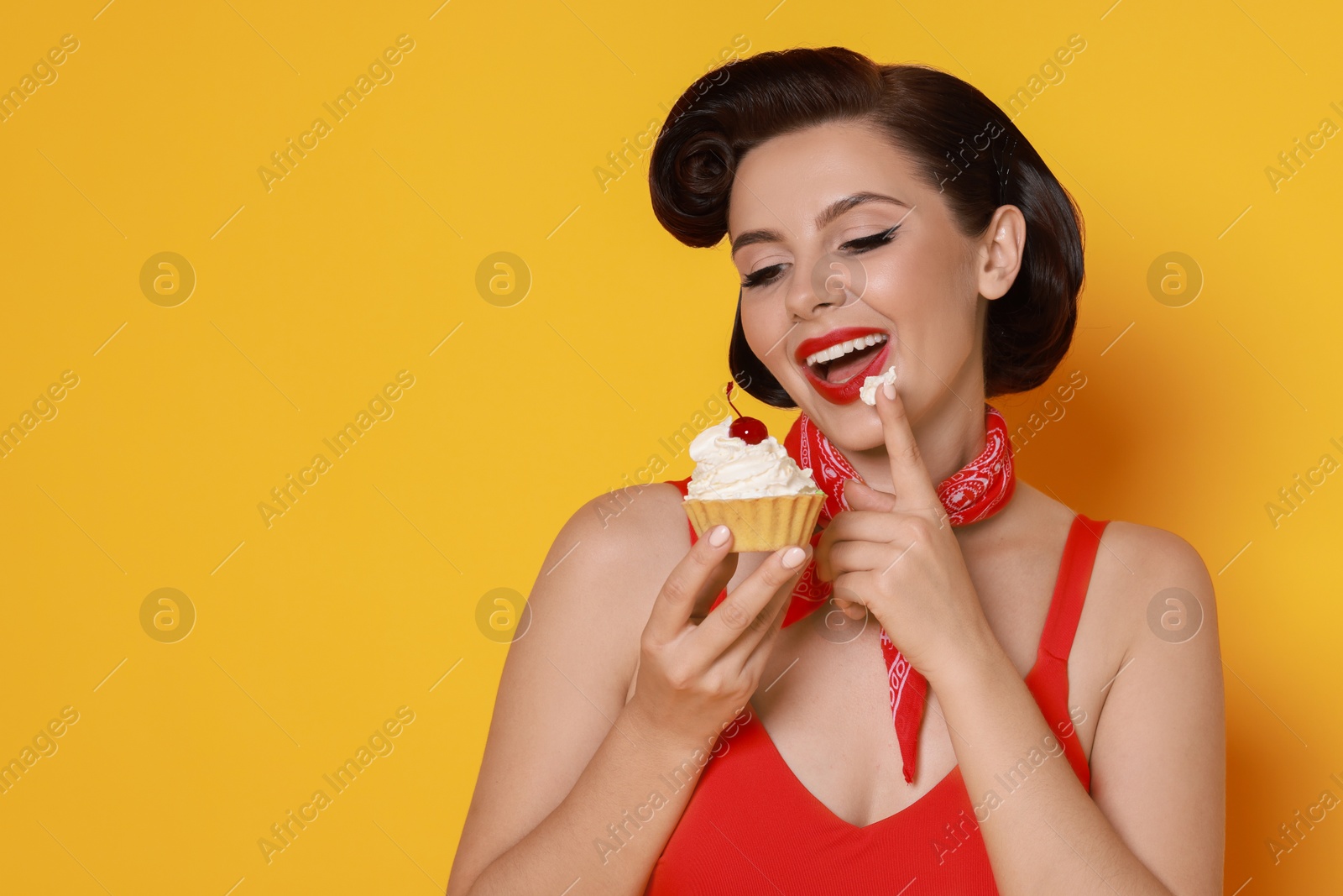 Photo of Pin-up woman eating cupcake on orange background, space for text