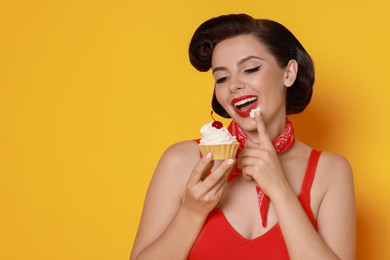 Photo of Pin-up woman eating cupcake on orange background, space for text